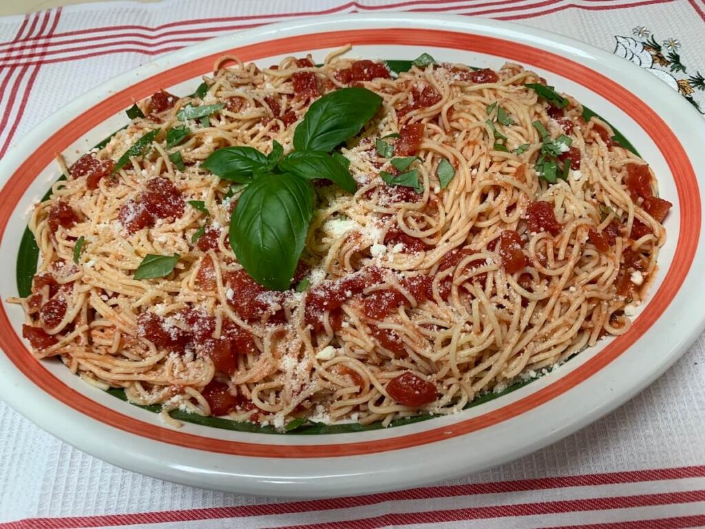 Cold garlic pasta salad made with Grandpa Pete’s Garlic Sauce, served on a platter with basil and Parmesan, perfect for summer cookouts.