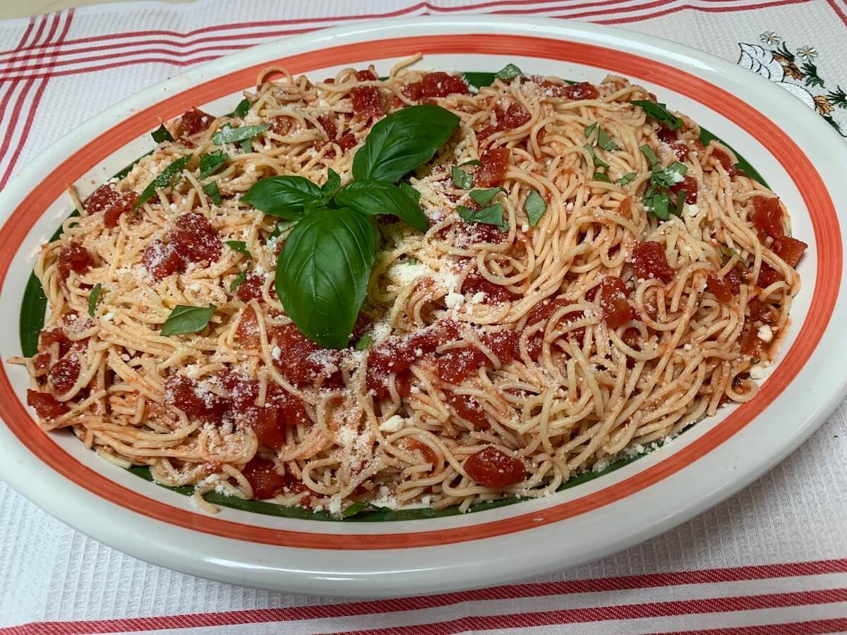 Cold garlic pasta salad made with Grandpa Pete’s Garlic Sauce, served on a platter with basil and Parmesan, perfect for summer cookouts.